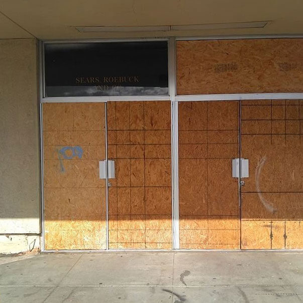 commercial building with boarded up doors and a window